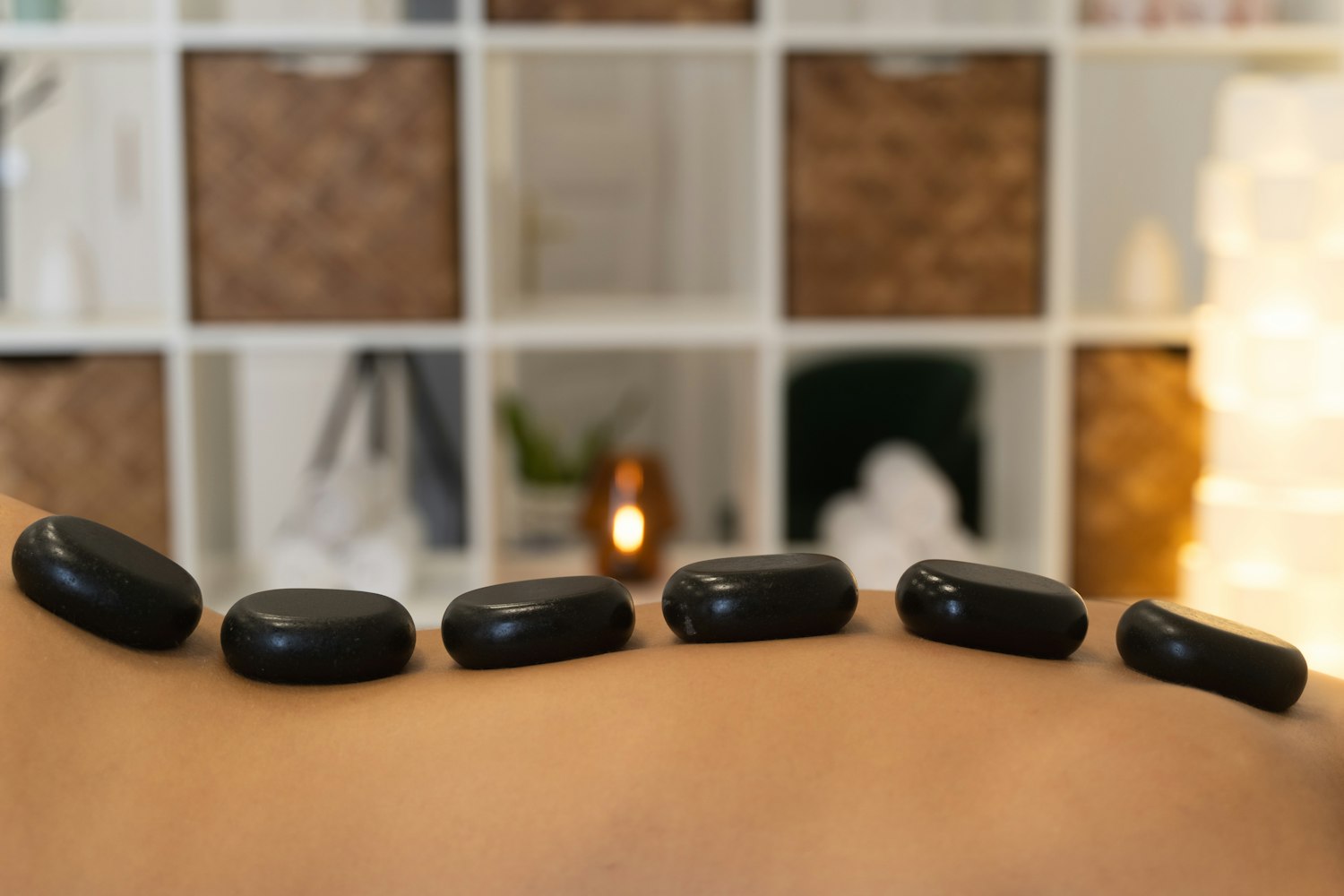 Smooth black basalt stones resting in a line along a person's back.